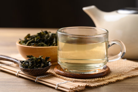 Hot green tea in cup glass, dried tea leaves and teapot on wooden background, Healthy drinkの写真素材