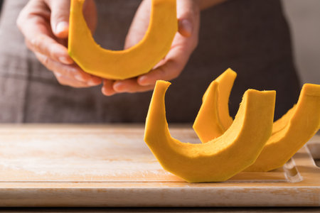 Section and peeled pumpkin holding by hand, Homemade cookingの写真素材