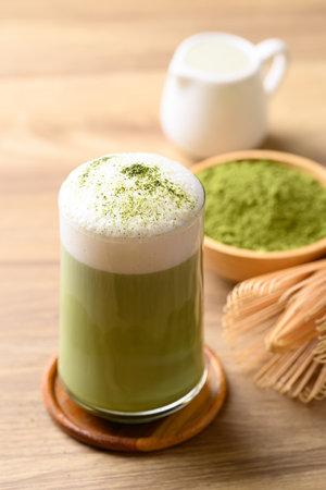 Matcha green tea with foam milk in glass on wooden backgroundの写真素材