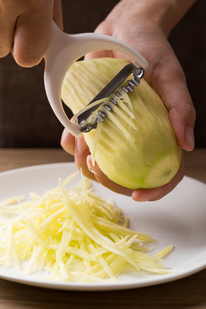 Hand holding grater and shredding green mango to make saladの写真素材