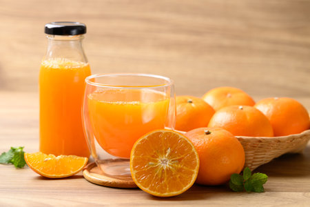 Orange juice in glass and bottle with fresh orange fruit in basket on wooden background, Healthy drinkの写真素材