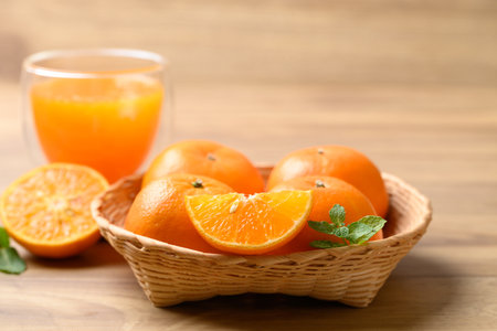 Fresh orange fruit in basket with orange juice on wooden background, Healthy drinkの写真素材