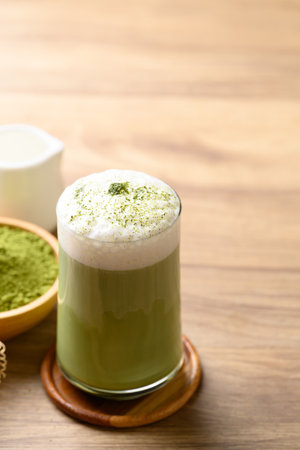 Matcha green tea with foam milk in glass on wooden backgroundの写真素材