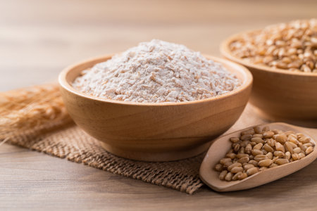 Whole wheat flour with wheat grain in bowl on wooden backgroundの写真素材