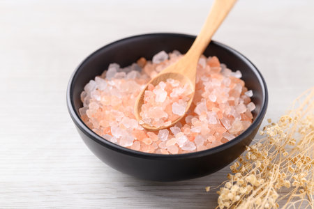 Organic Himalayan pink salt in black bowl with spoon on white table, Healthy food ingredientの写真素材