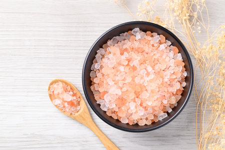 Organic Himalayan pink salt in black bowl with spoon on white table, Healthy food ingredient, Top viewの写真素材