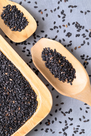 Black sesame seed in wooden spoon and plate, Healthy eating, Top viewの写真素材