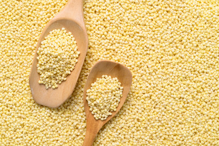 Yellow millet grain background with wooden spoon, Food ingredient, Top viewの写真素材