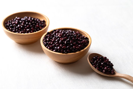 Raw Azuki beans or red mung beans in wooden bowl and spoon on white background, Food ingredientの写真素材