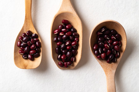 Top view of raw Azuki beans or red mung beans in wooden spoon on white background, Food ingredientの写真素材