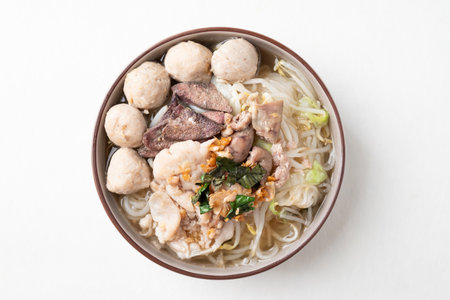 Thai noodles soup with sliced pork, minced pork, meatball and liver in a bowl on white background, Traditional Thai street food, Top viewの写真素材