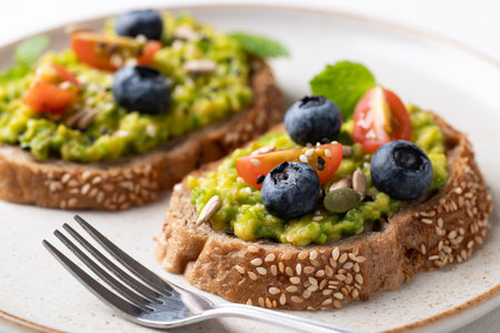 Avocado toast with blueberries, cherry tomatoes, sunflower seeds, pumpkin seeds, sesame seeds and other grain on plate, Healthy eatingの写真素材