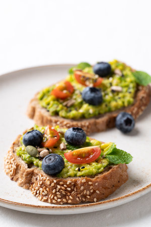 Avocado toast with blueberries, cherry tomatoes, sunflower seeds, pumpkin seeds, sesame seeds and other grain on plate, Healthy eatingの写真素材