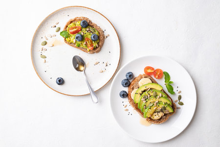 Avocado toast with banana, sunflower seeds, pumpkin seeds, sesame seeds, blueberries, tomatoes and...