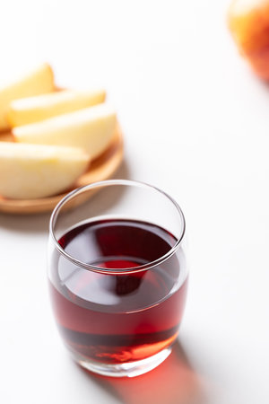 Glass of apple cider with sliced red apple fruit on white backgroundの写真素材