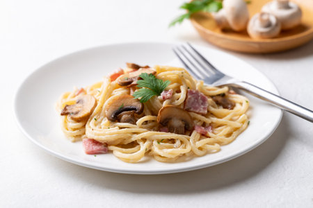 Spaghetti carbonara with ham, bacon and champignon mushroom on plate with white background, Italian foodの写真素材