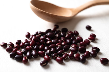 Pile of raw Azuki beans or red mung beans with wooden spoon on white background, Food ingredientの写真素材