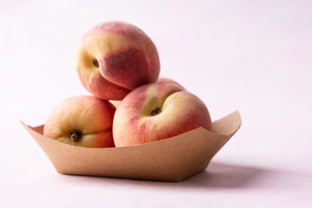 Fresh peaches in paper bowl on pink background, Summer fruitの写真素材