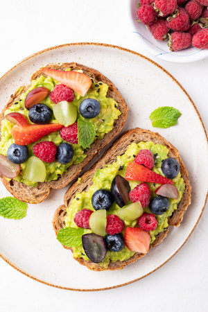 Top view of avocado toast with strawberry, blueberry, raspberry and grape.の写真素材