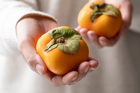 Fresh ripe persimmon holding by woman hand, Autumn sweet fruit