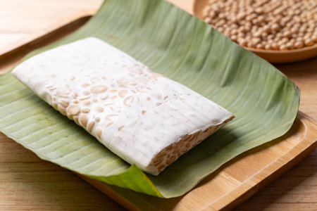 Raw tempeh made from fermented soybeans wrapped by banana leaf, Traditional Indonesian food, Healthy vegan and plant based ingredientsの写真素材