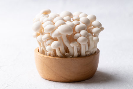 Fresh white Shimeji mushroom in wooden bowl on white background, Asian edible mushroom, Food ingredientsの写真素材