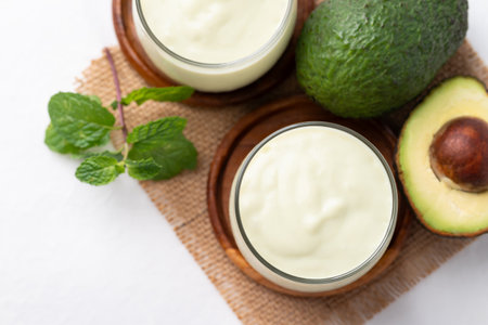 Avocado smoothie with milk in glass and avocado fruit on white backgroundの写真素材