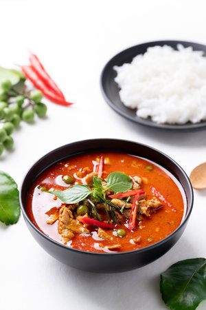 Thai red curry with pork and cooked rice with ingredients on white backgroundの写真素材