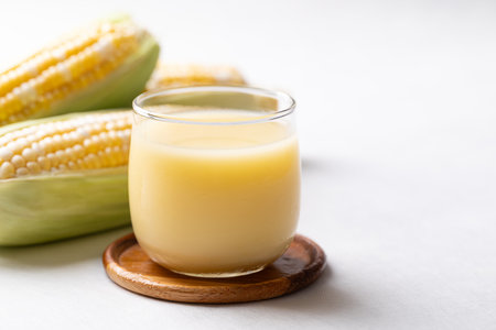Sweetcorn milk in glass and fresh sweetcorn on white background, Alternative milk from plant, dairy freeの写真素材