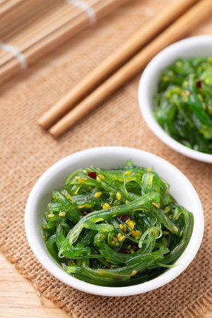 Wakame seaweed salad with sesame seed in a bowl with chopsticksの写真素材