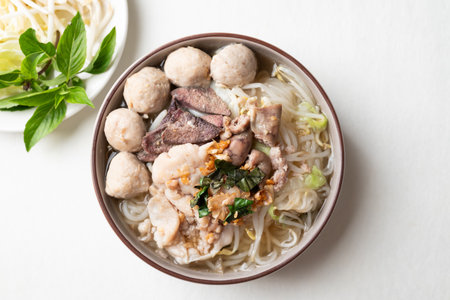 Thai noodles soup with sliced pork, minced pork, meatball and liver in a bowl eating with fresh...