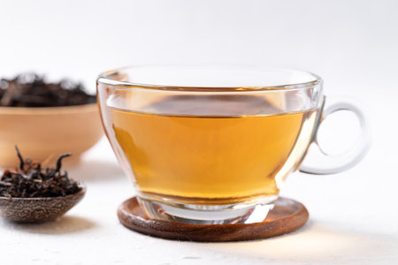 Black tea in cup glass with dried tea leaves on white background, Healthy herbal hot drinkの写真素材