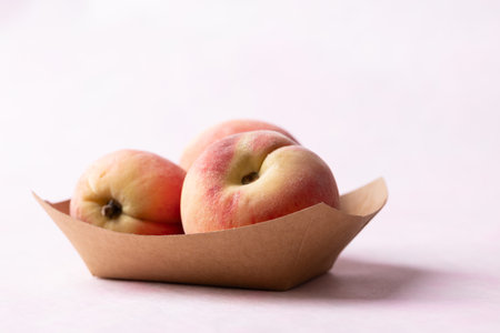 Fresh peaches in paper bowl on pink background, Summer fruitの写真素材