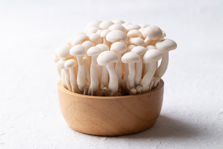 Fresh white Shimeji mushroom in wooden bowl on white background, Asian edible mushroom, Food ingredientsの写真素材