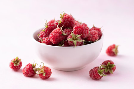 Fresh ripe raspberry with leaf in bowl on pink background, Summer fruit