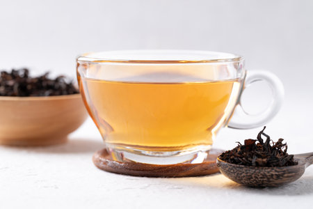 Black tea in cup glass with dried tea leaves on white background, Healthy herbal hot drink