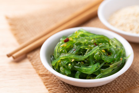 Wakame seaweed salad with sesame seed in a bowl on wooden backgroundの写真素材