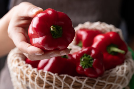 Fresh red bell pepper or sweet pepper in mesh bag with handの写真素材