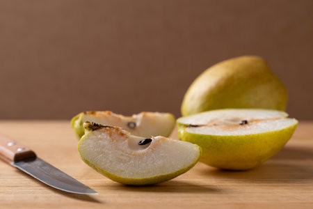 Sliced pear on cutting wooden board with kitchen knifeの写真素材