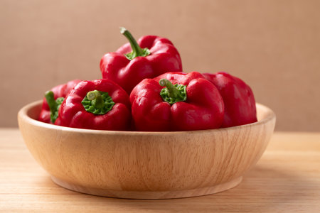 Fresh red bell pepper or sweet pepper in a bowl on wooden background