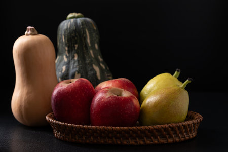 Red apple, pear and butternut squash on black backgroundの写真素材