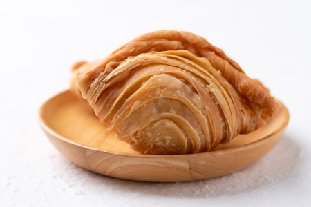 Curry puff stuffed with chicken or sweet potatoes on wooden plate with white background, Thai snack food styleの写真素材