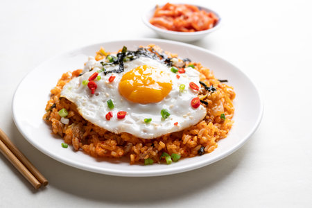 Kimchi fried rice with fried egg, pork, sesame seed, chili, spring onion and seaweed on white plate, Korean foodの写真素材