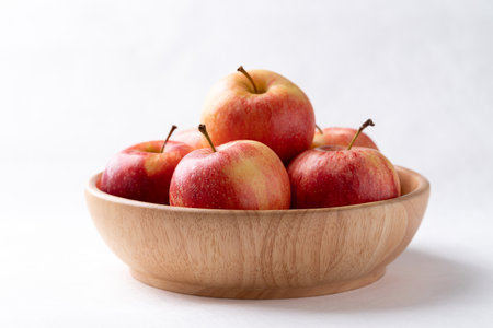 Red apple fruit in wooden bowl on white background