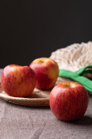 Red apple fruit in basket on brown fabric with black background