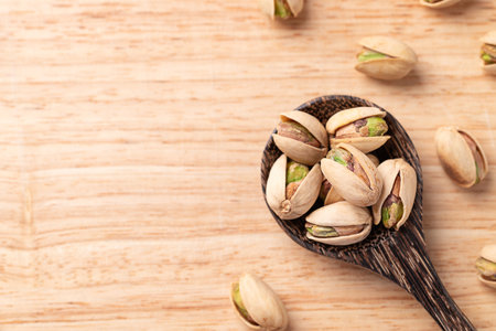 Roasted Pistachio nuts in a spoon on wooden background, Table top viewの写真素材