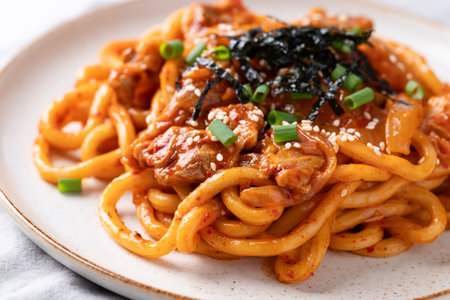 Stir fried Udon noodle with kimchi cabbage, pork, spring onion, sesame seed and seaweed on topの写真素材