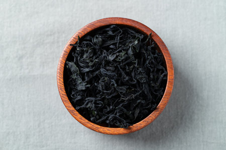 Top view of dried wakame seaweed in a wooden bowl on a fabric background, Healthy Asian food ingredientの写真素材