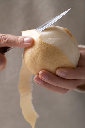 Close-up of a hand using a paring knife for cutting a fresh Asian pearの写真素材