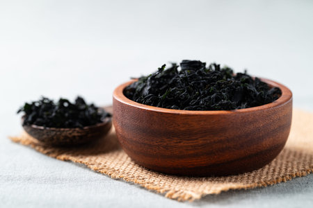 Dried wakame seaweed in a wooden bowl and spoon, Healthy Asian food ingredientの写真素材